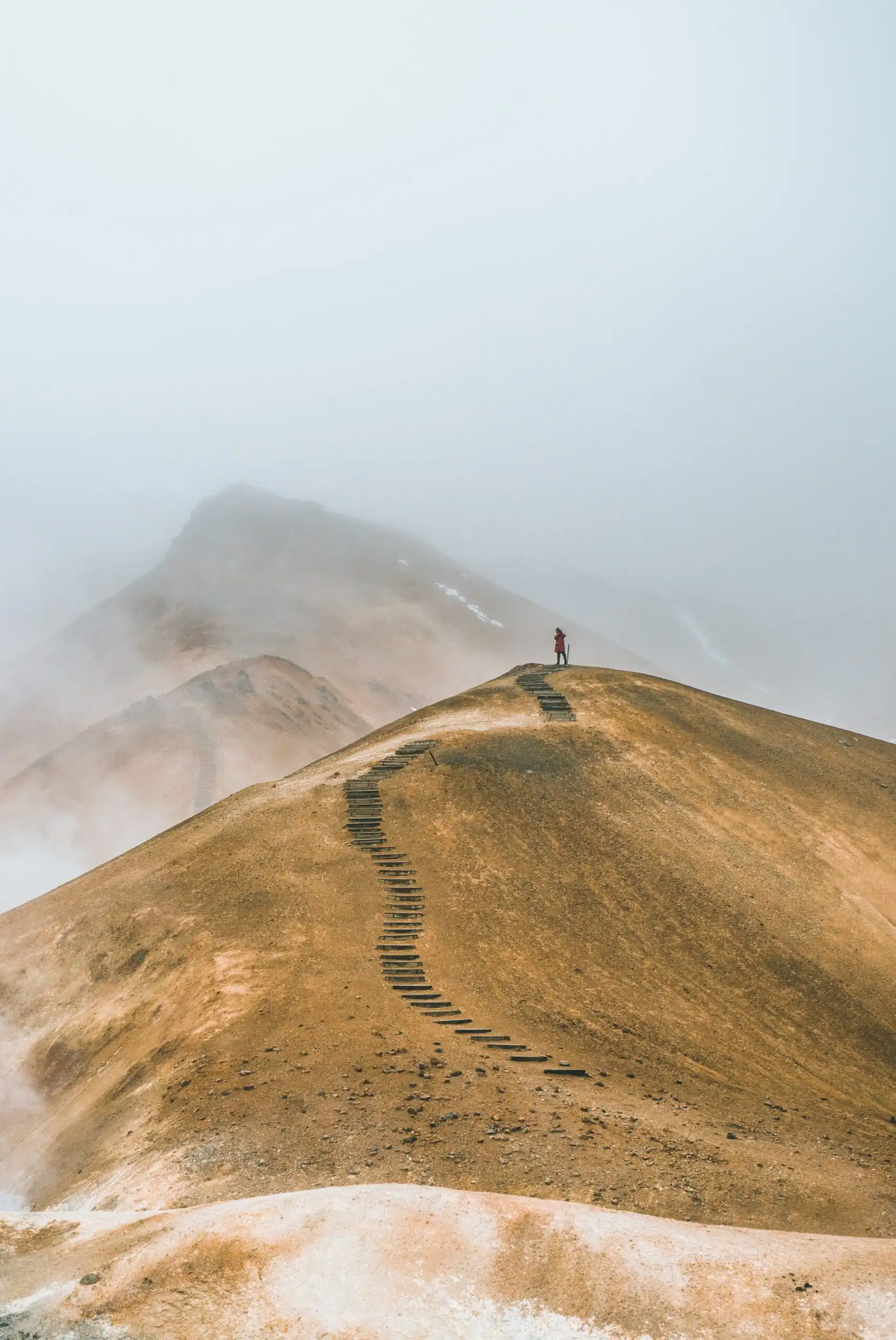 Un homme, accompagné par un coaching professionnel, marche sur un chemin de montagne vers les sommets